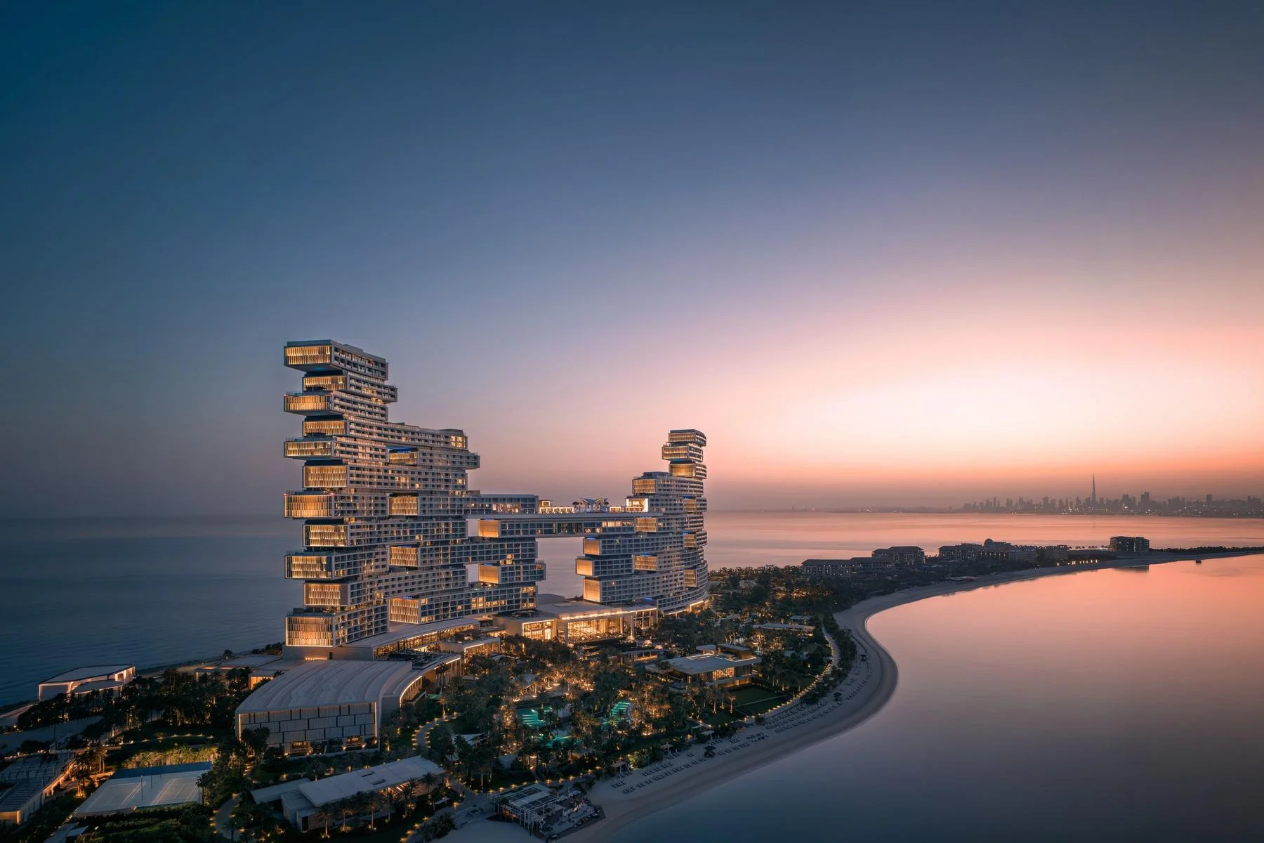 Arquitetura de volumes empilhados do Atlantis The Royal junto ao mar ao crepúsculo