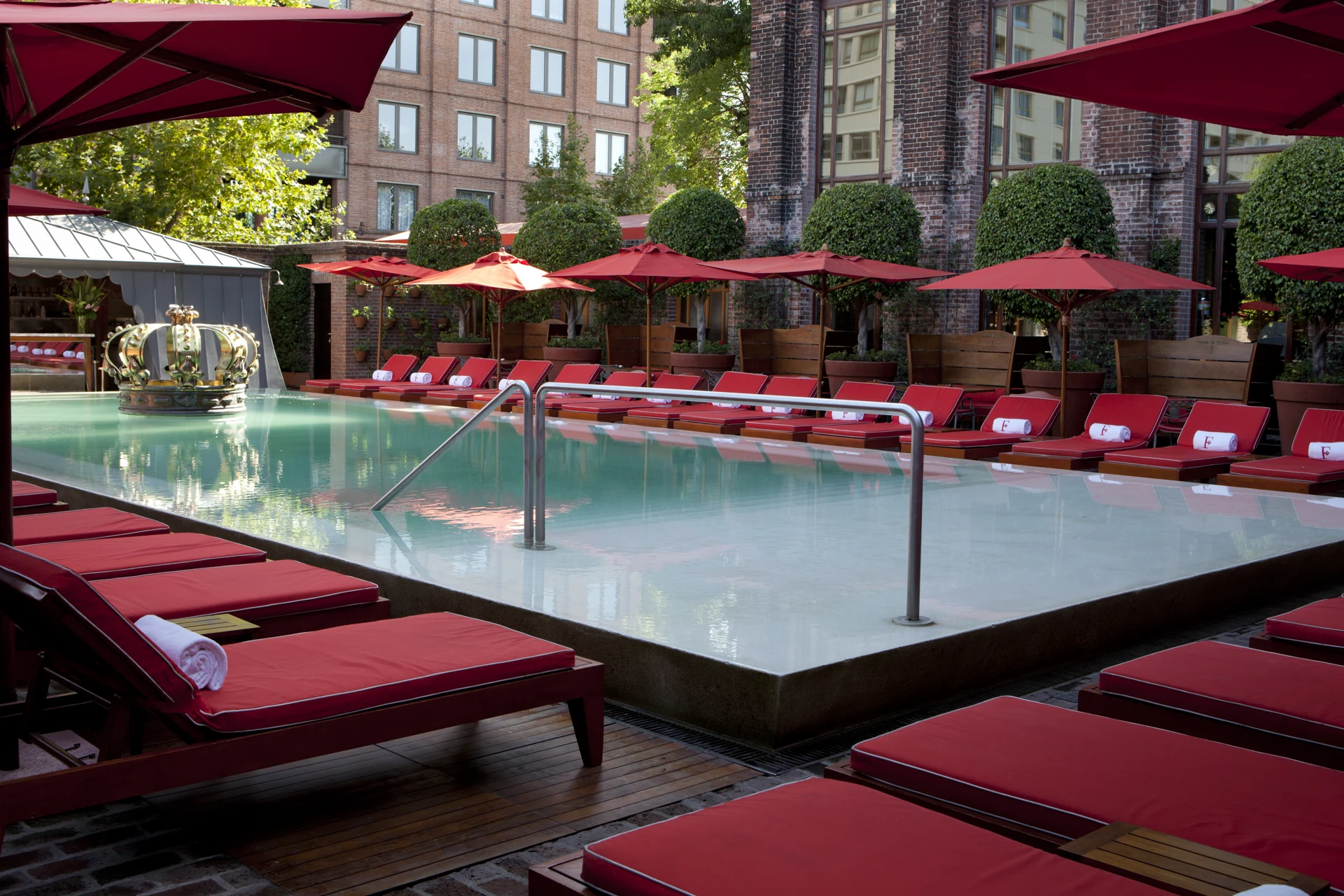 Piscina com fonte em forma de coroa e espreguiçadeiras vermelhas no Faena Buenos Aires