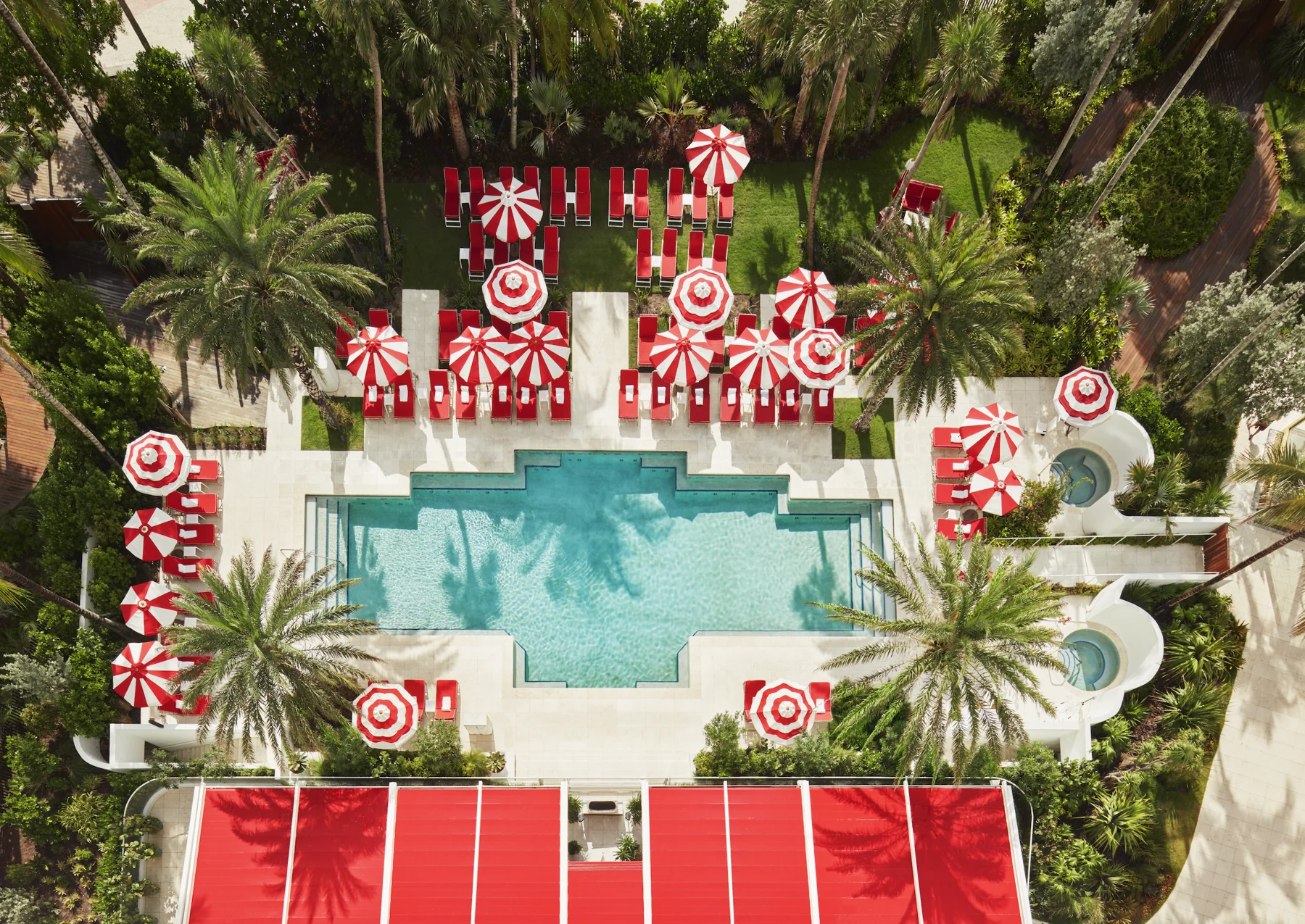 Piscina do Faena Miami Beach rodeada por guarda-sóis vermelhos e brancos