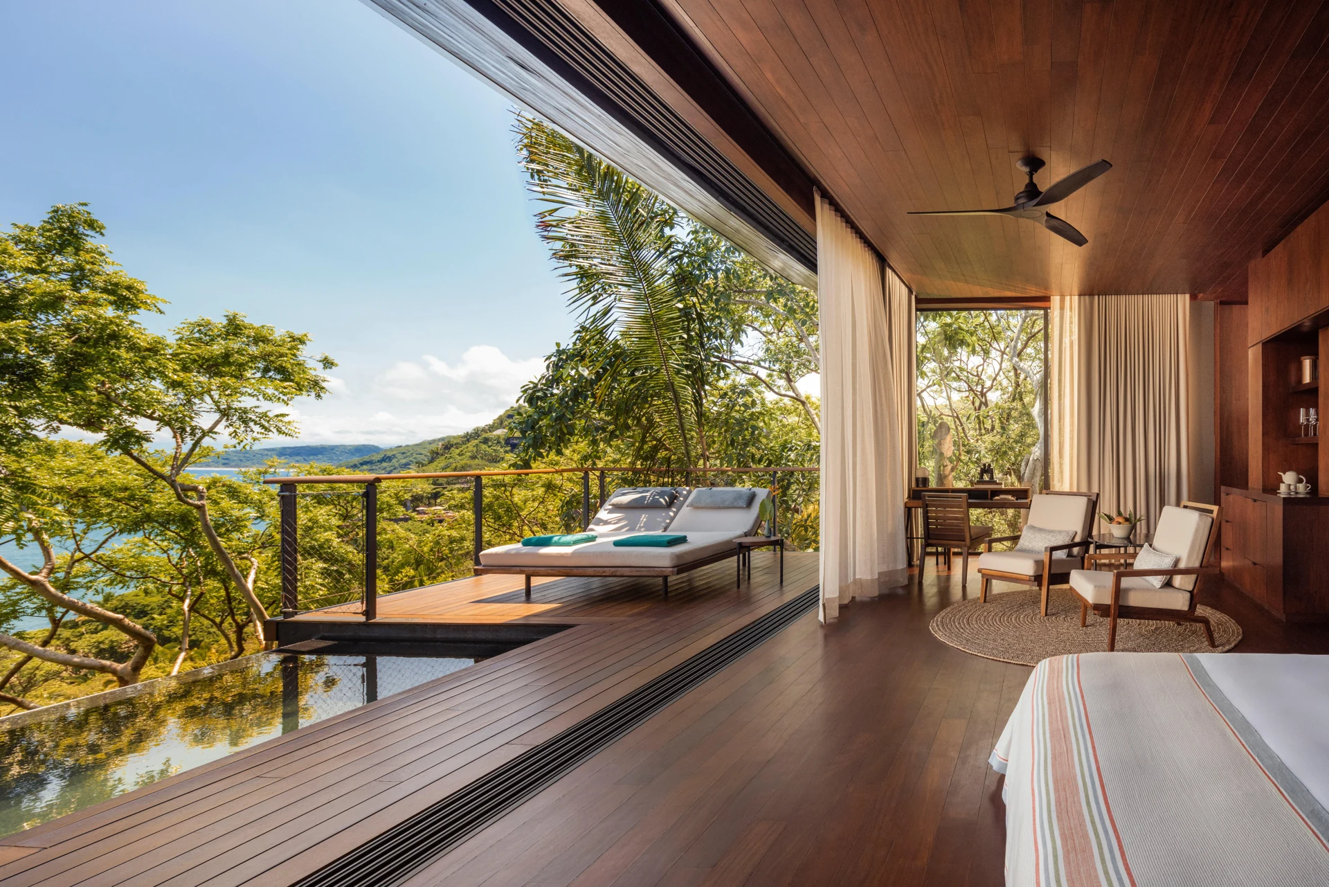 Quarto de uma casa entre as árvores com varanda aberta à mata