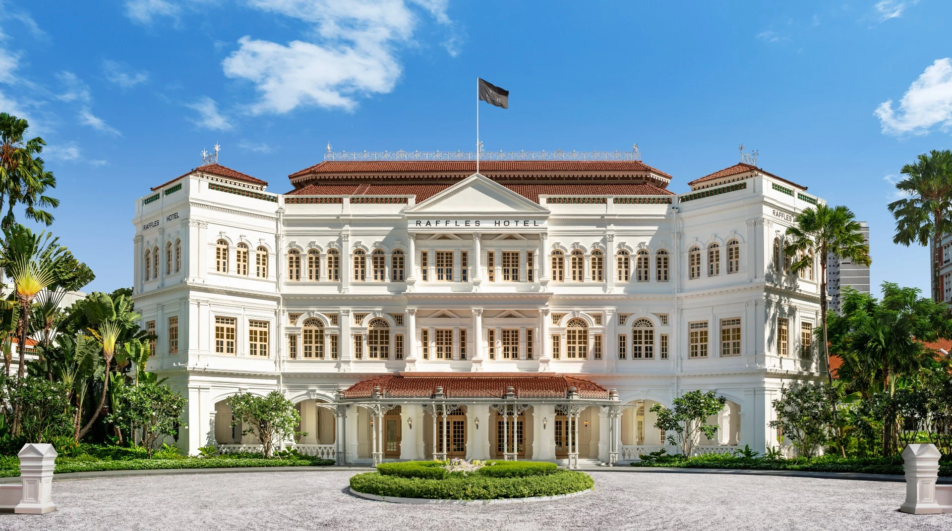Fachada histórica branca do Raffles Singapore com palmeiras