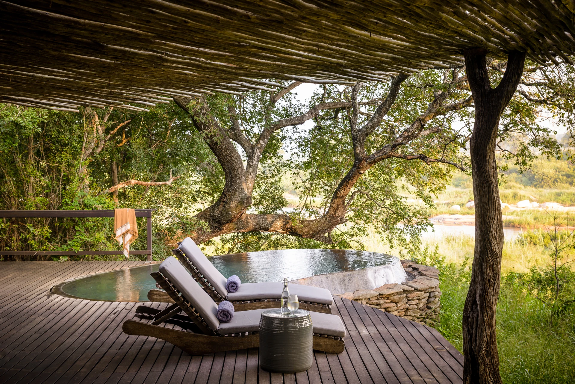 Deck e piscina privativa de uma suíte do Singita Boulders Lodge junto à vegetação do rio