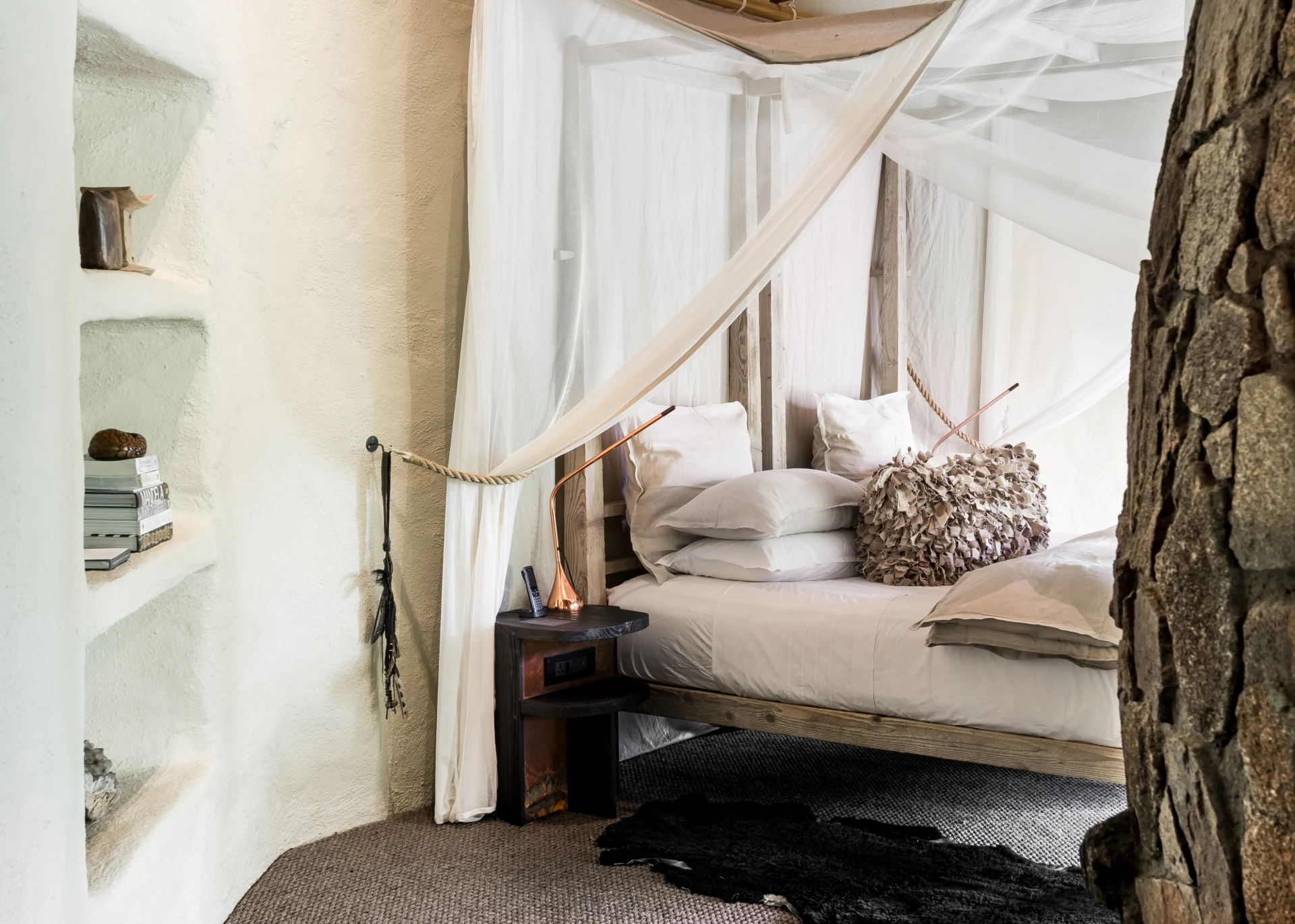 Suíte do Singita Boulders Lodge com materiais naturais e cama com dossel