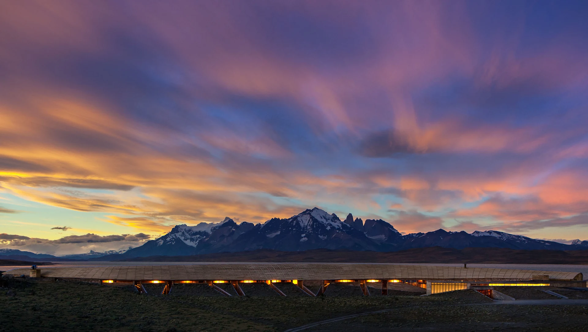 Arquitetura curva do Tierra Patagonia junto ao lago Sarmiento e montanhas ao pôr do sol